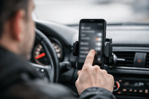 Водитель настраивает смартфон в салоне припаркованной машины